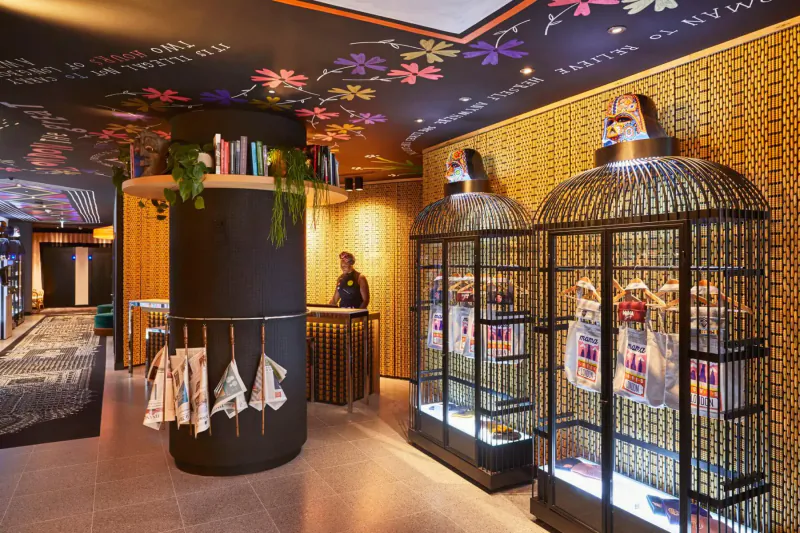 Stylish Mama London gallery interior with floral walls, large birdcages, bookshelves, bar, and staff for Halloween fun.