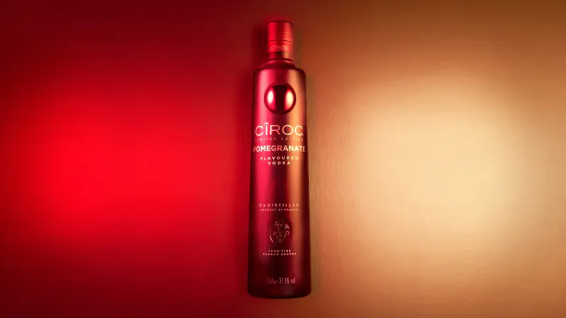 Cîroc Vodka bottle with red gradient label, lit in festive red and orange glow.
