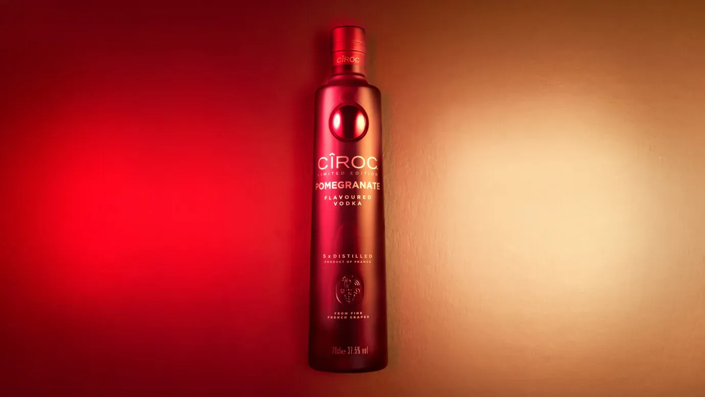 Cîroc Vodka bottle with red gradient label, lit in festive red and orange glow.