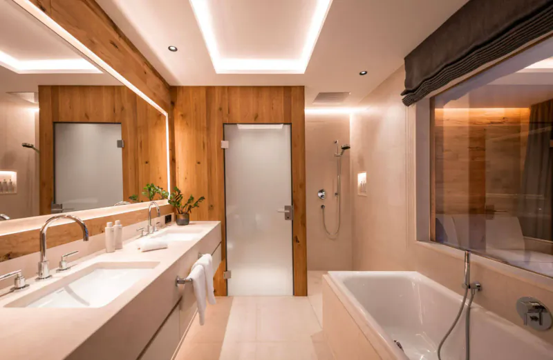 Luxurious wooden chalet bathroom with double sink vanity, bathtub, shower, and ambient lighting.