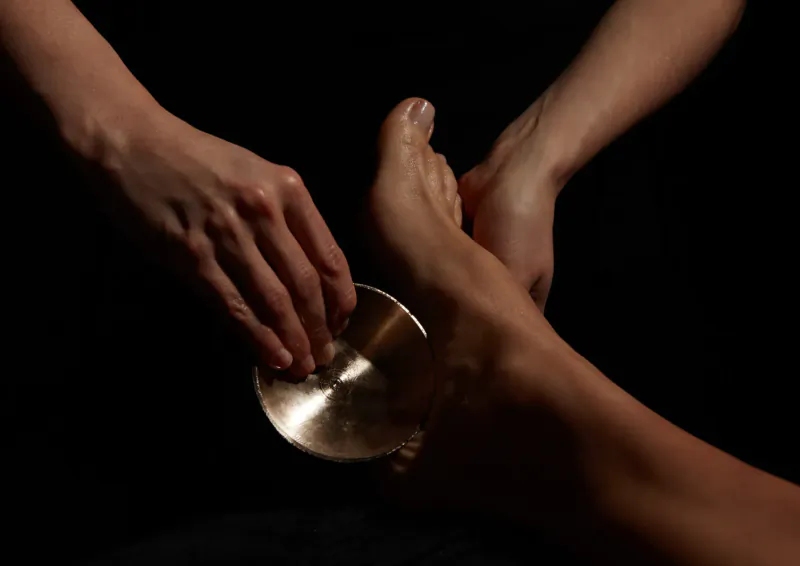 Hands massaging foot with gold singing bowl in ESPA spa treatment