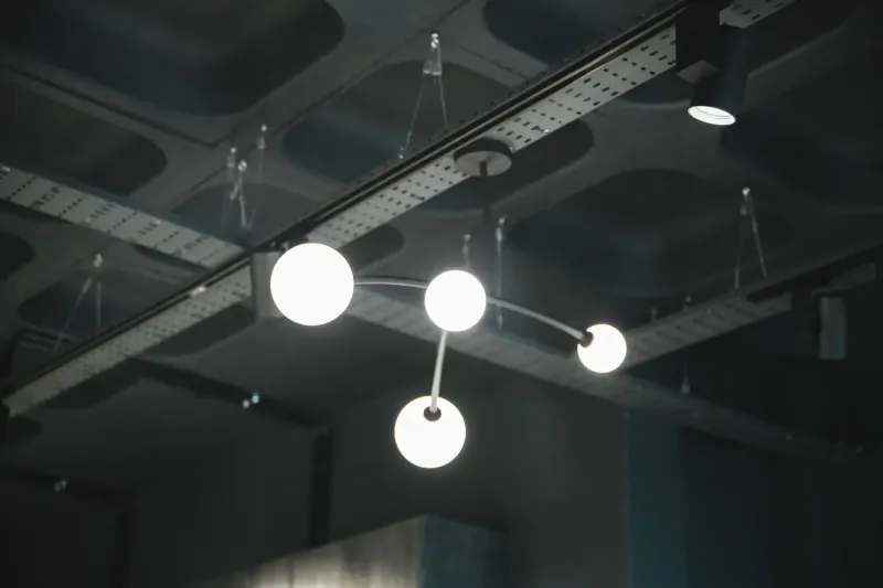 Modern four white orb pendant light fixture hanging from industrial ceiling track in gallery