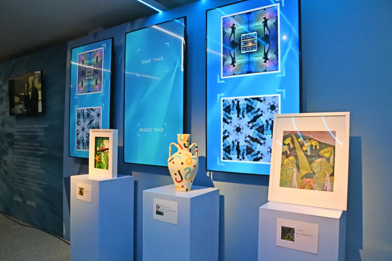 AI art gallery at Design Museum: New York text screens, geometric framed prints, decorated vase on pedestal, landscape paintings.