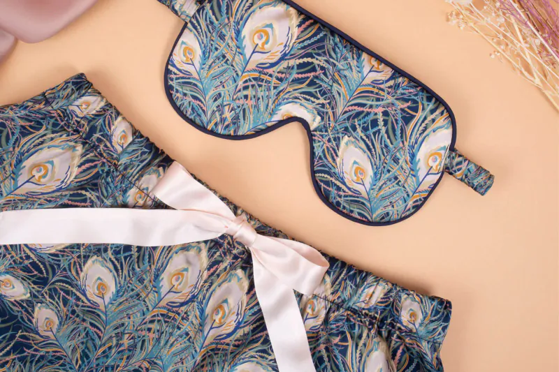 Peacock print sleep mask and matching shorts with white satin bow on neutral background
