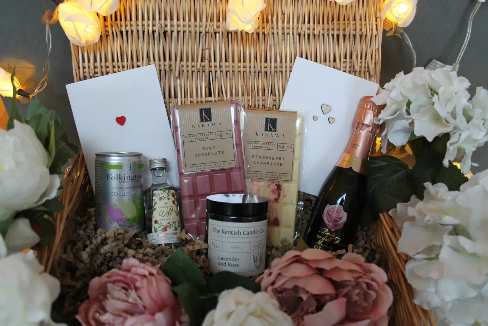 Valentine's charity gift basket with fairy lights, champagne, chocolates, candles, bath bomb, flowers, and cards from Kentish Candle Co.