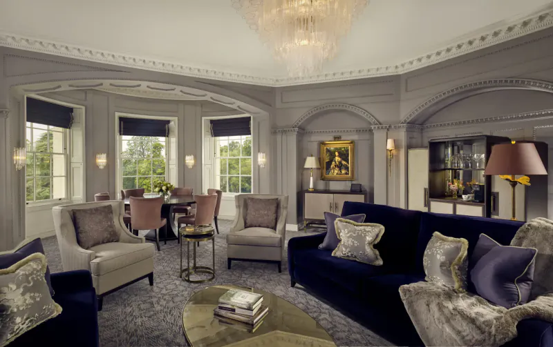 Elegant lounge in The Langley luxury hotel with chandelier, velvet sofas, armchairs, coffee table, and garden views.