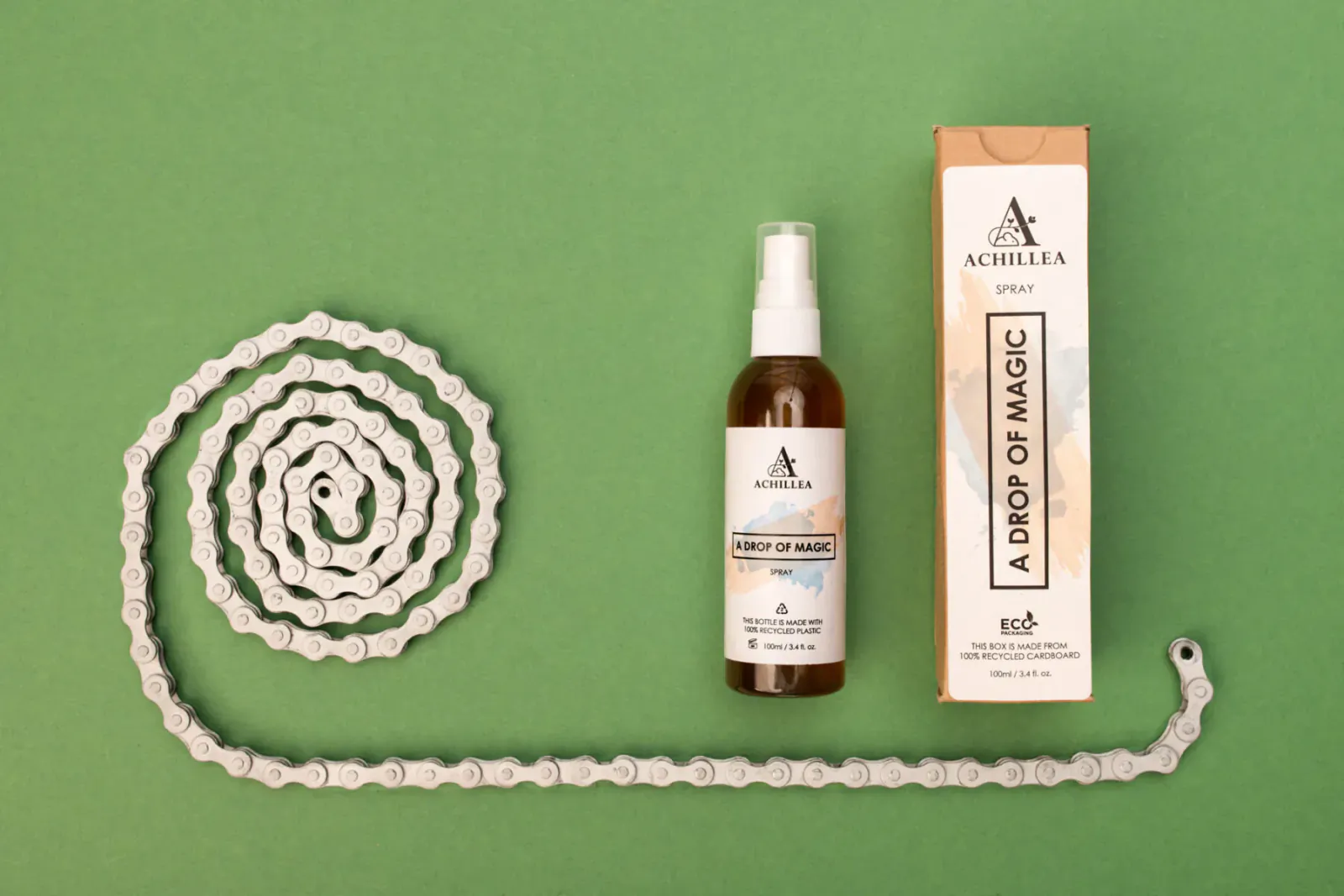 Achillea 'Drop of Magic' brown spray bottle and box beside coiled bike chain on green background
