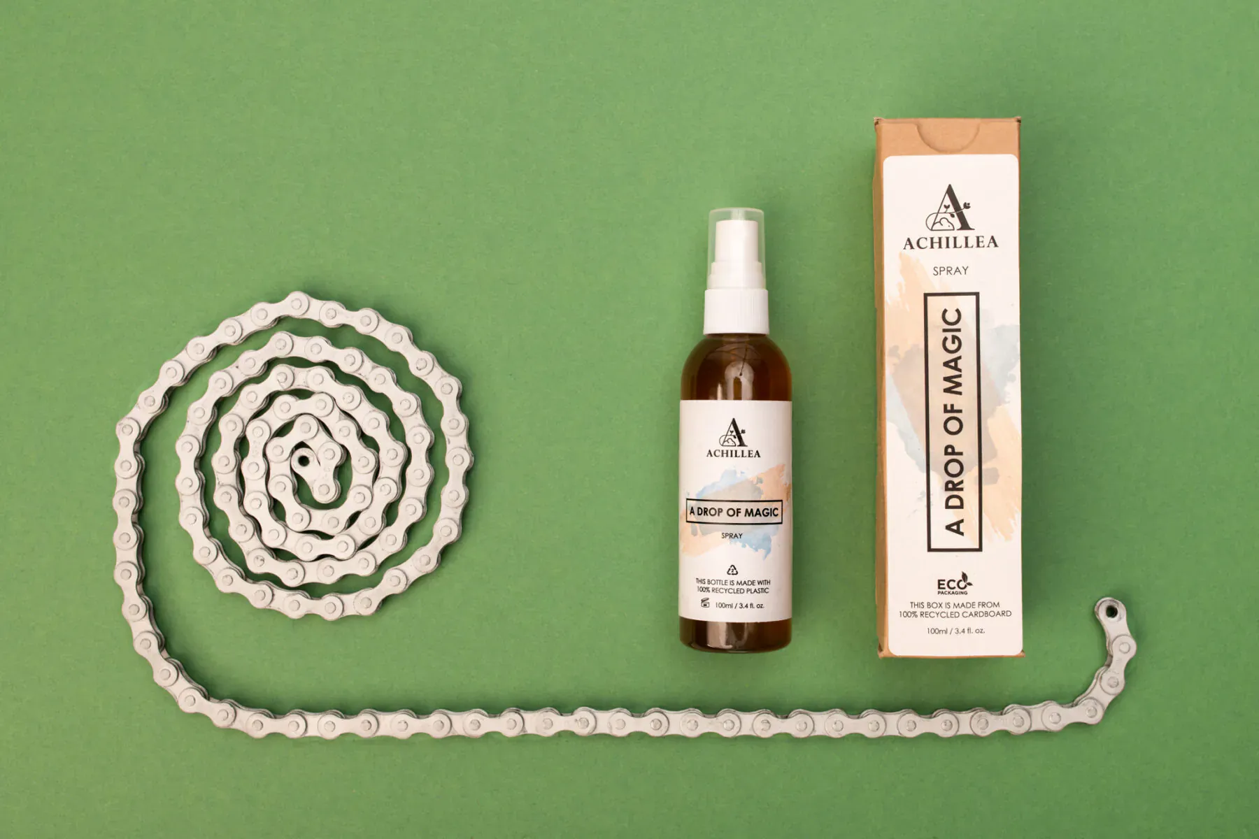 Achillea 'Drop of Magic' brown spray bottle and box beside coiled bike chain on green background