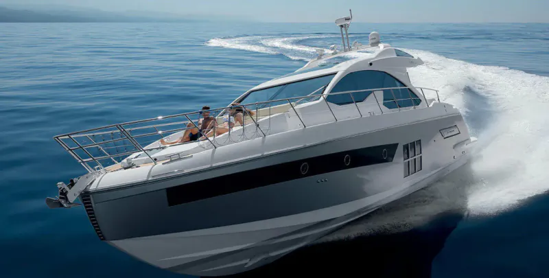 White luxury yacht speeding on blue ocean, two women lounging on deck, creating white wake trails.