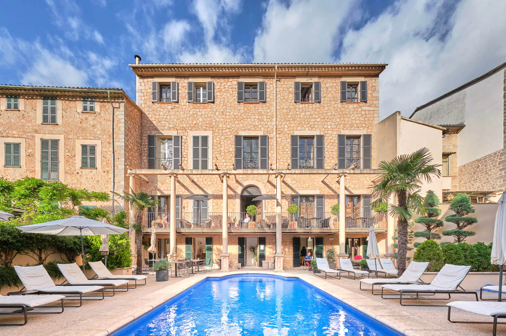 L’Avenida adults-only hotel in Majorca: sandstone building with pool, loungers, palms under blue sky