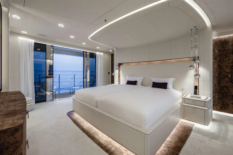 Luxurious superyacht master bedroom with twin white beds, open doors to ocean balcony, wood accents, ambient lighting.