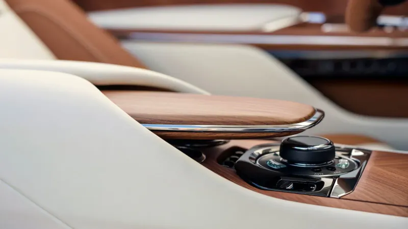 Close-up of Arcadia Droptail's luxury wood-trimmed center console with black control knob and white leather armrest