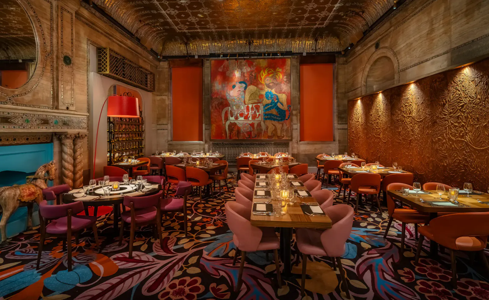 Masala Zone Piccadilly Circus grand brasserie interior with ornate ceiling, abstract orange wall art, round tables, colorful chairs, and candlelit settings