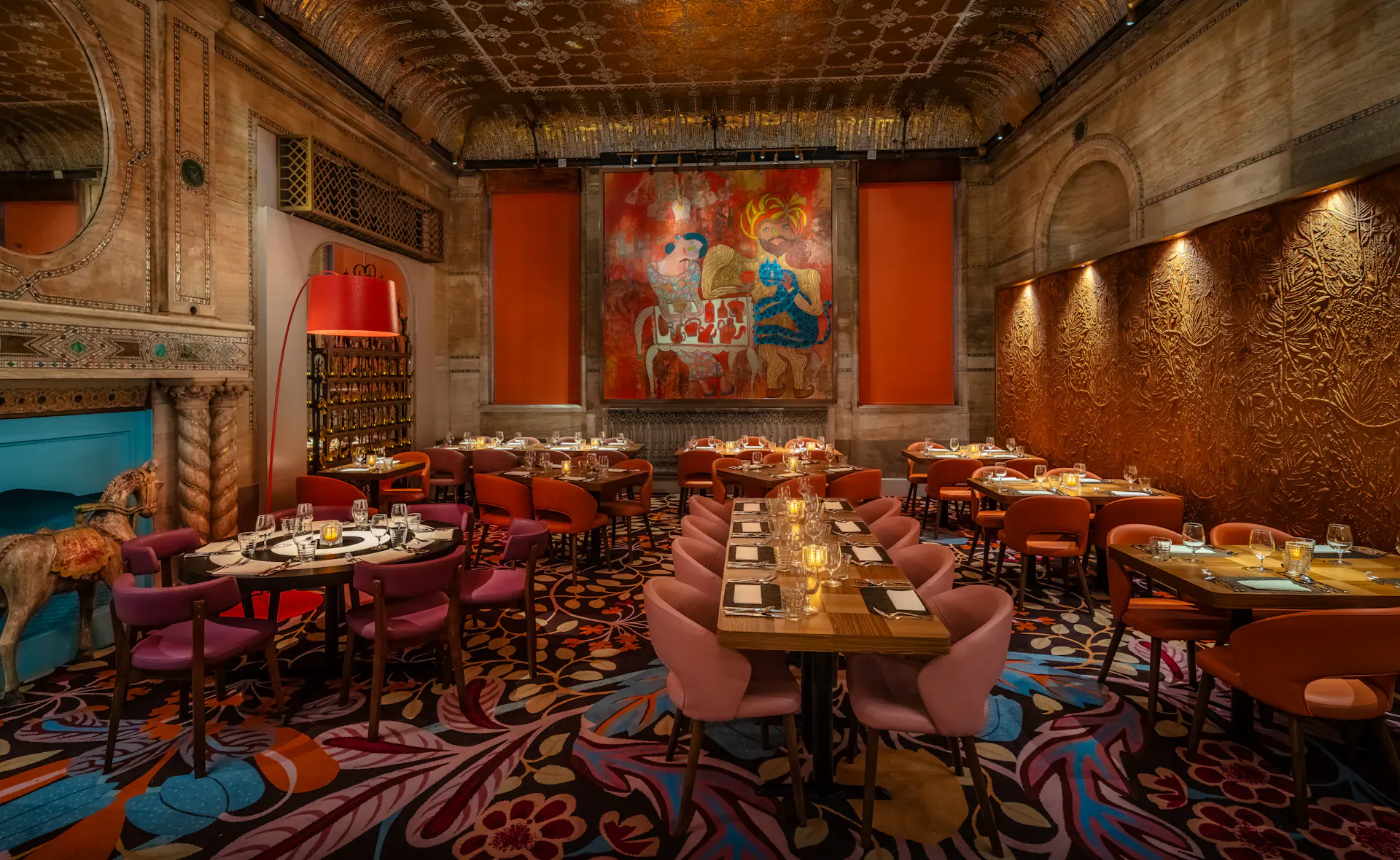 Masala Zone Piccadilly Circus grand brasserie interior with ornate ceiling, abstract orange wall art, round tables, colorful chairs, and candlelit settings