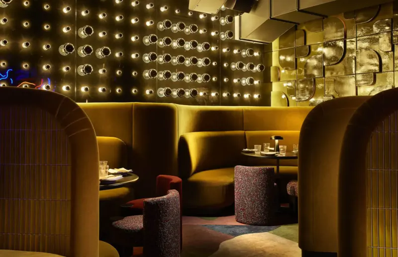 Chotto Matte Soho gallery: luxurious yellow velvet booth seating, round tables with glasses, glowing dotted wall backdrop