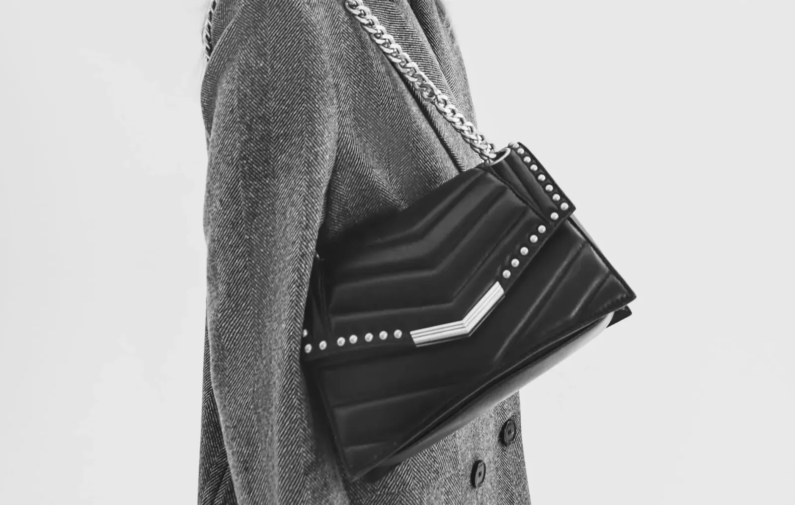 Model in gray coat holding black quilted chain-strap handbag with studs, IKKS Paris fashion