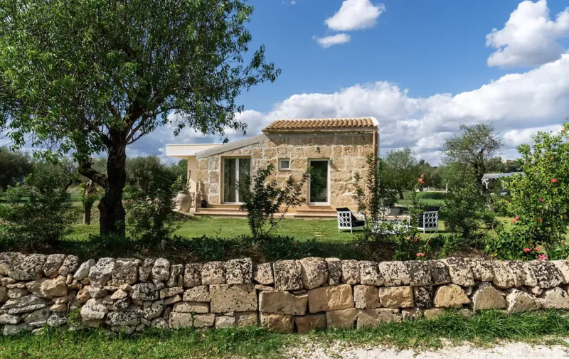 Stone Zahir Country House in Sicilian countryside, surrounded by olive trees, garden, stone wall, blue sky with clouds