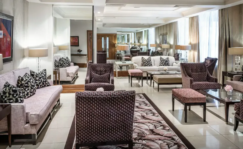 Elegant hotel gallery lounge at The Bristol with plush sofas, armchairs, mirrors, lamps, and patterned rug.