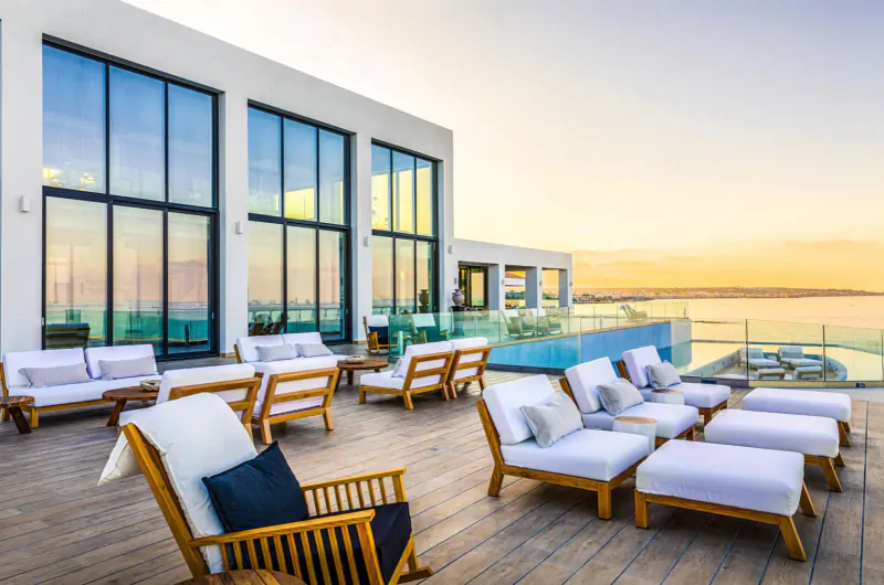 Luxury rooftop terrace at Abaton Island Resort with white lounge chairs, sunset ocean view