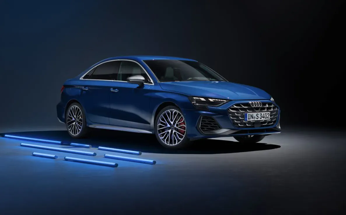 Blue Audi S3 sedan with 'S3' badge, angled front view on glowing blue light strips in dark studio.