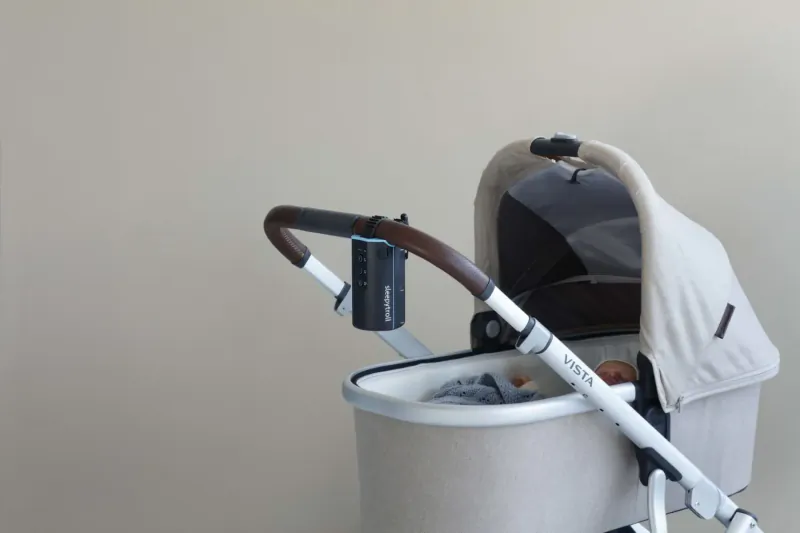 White Bugaboo Fox stroller with attached blue cup holder on handlebar, hood up, against plain wall.