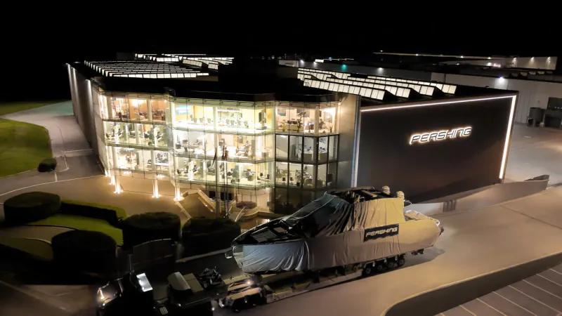 Night aerial view of Pershing GTX70 gallery with illuminated glass facade and first unit boat under cover outside