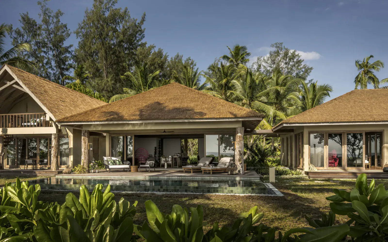 Four Seasons Desroches five-bedroom villa with infinity pool, open verandas, lounge seating, surrounded by palms and beachfront greenery.