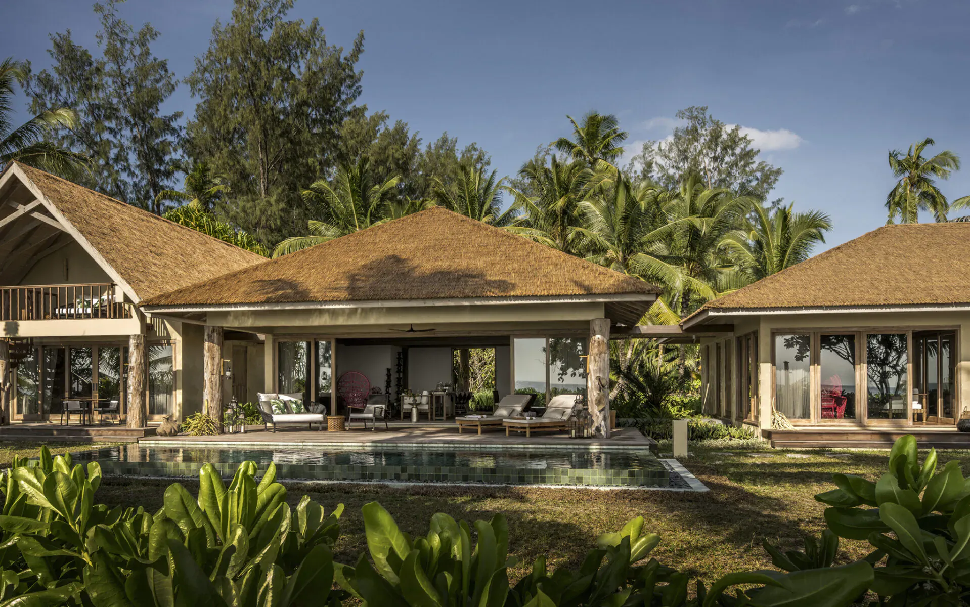Four Seasons Desroches five-bedroom villa with infinity pool, open verandas, lounge seating, surrounded by palms and beachfront greenery.