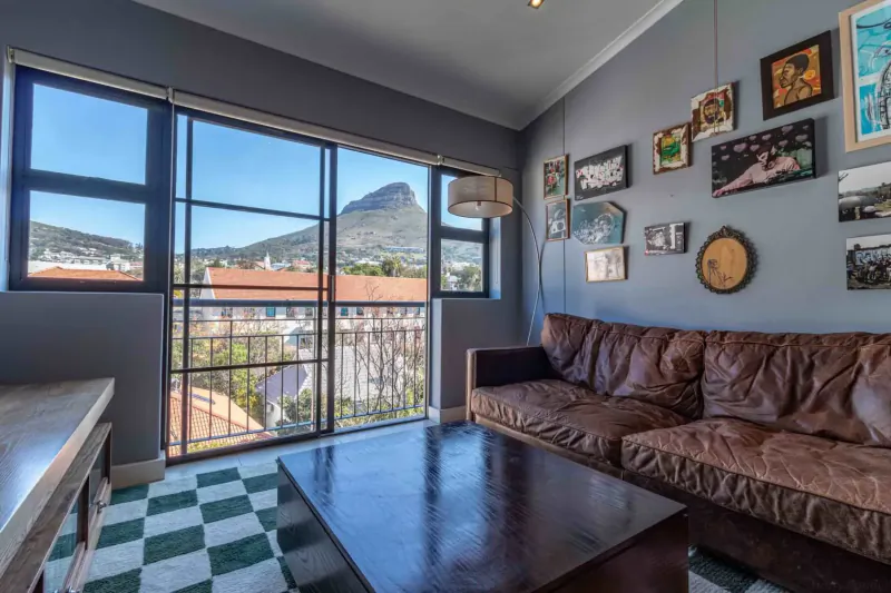 Modern lounge at Hippo Boutique Hotel with brown leather sofas, art wall, and panoramic view of Table Mountain.