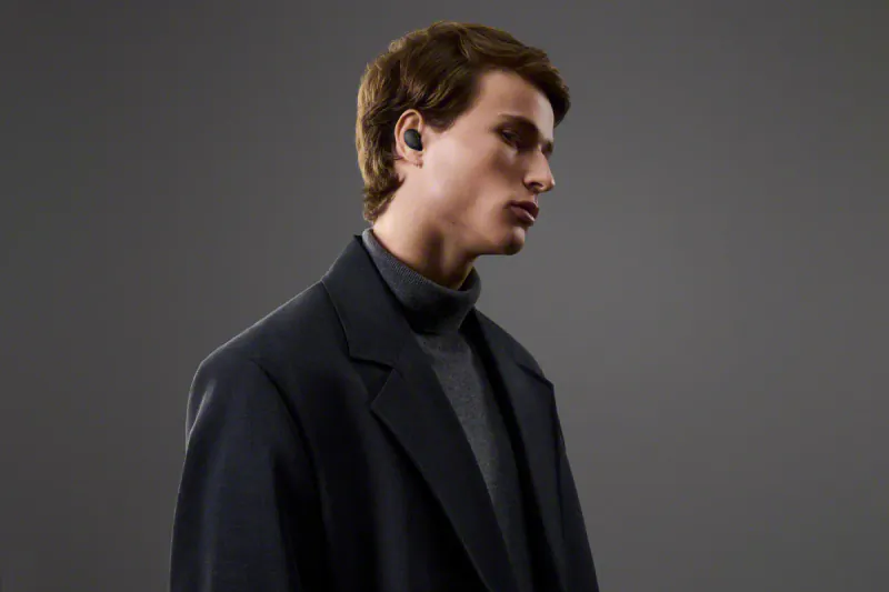 Side profile of young man in navy blazer and turtleneck wearing Sony WF-1000XM6 wireless earbuds