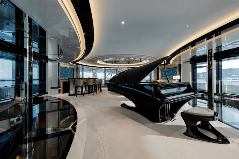 Luxurious yacht interior with grand black grand piano, curved walls, bar stools, and panoramic sea views.