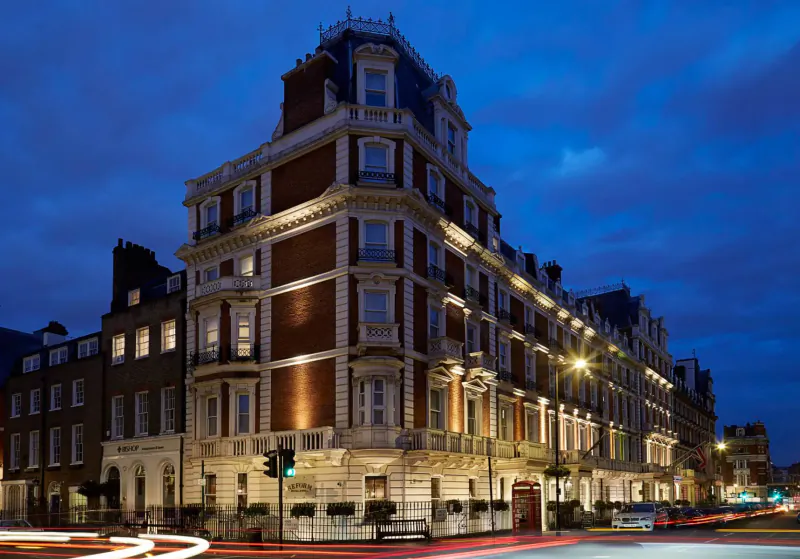 Elegant Victorian corner building illuminated at dusk in Marylebone Village, London, with streetlights and light trails.