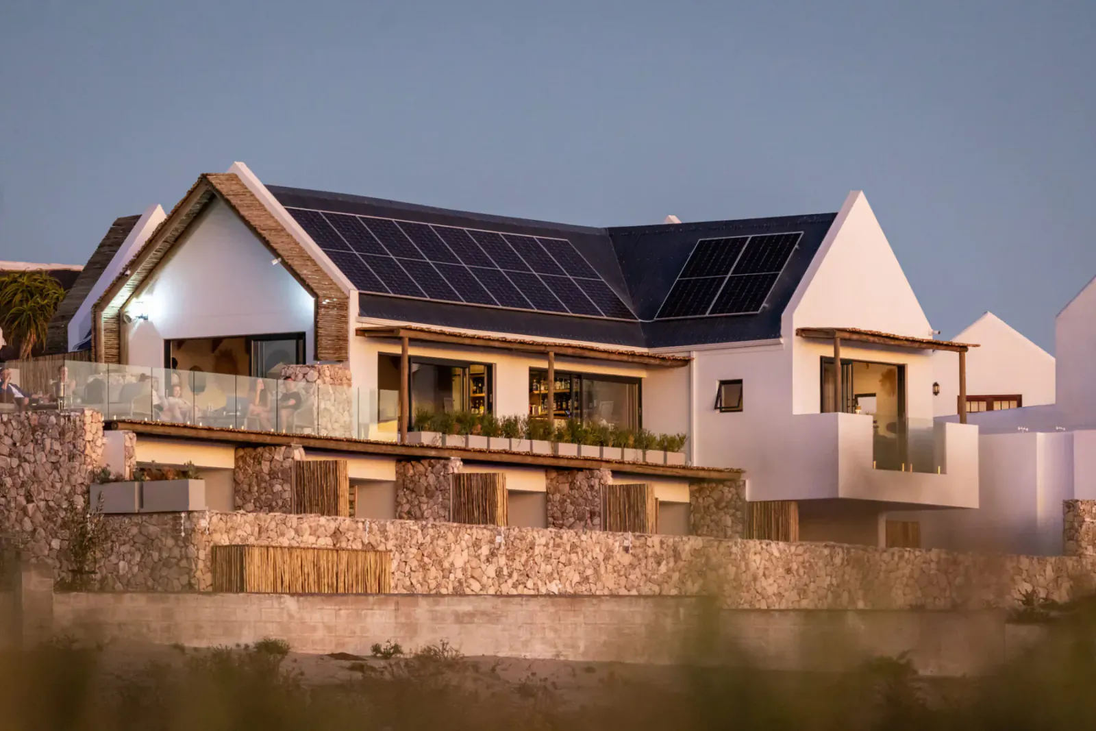 Modern white Oyster Suites villas with solar panels and balcony lounge at Abalone Hotel, coastal sunset view