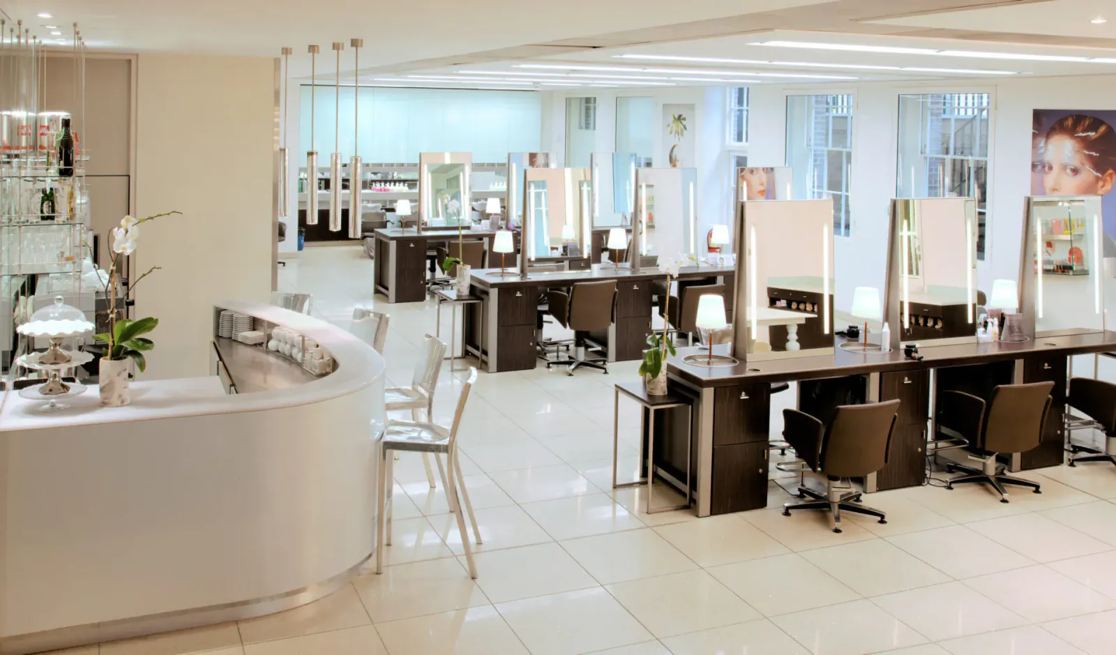 Modern Daniel Galvin salon with curved reception desk, multiple styling stations, chairs, and large hair model poster.