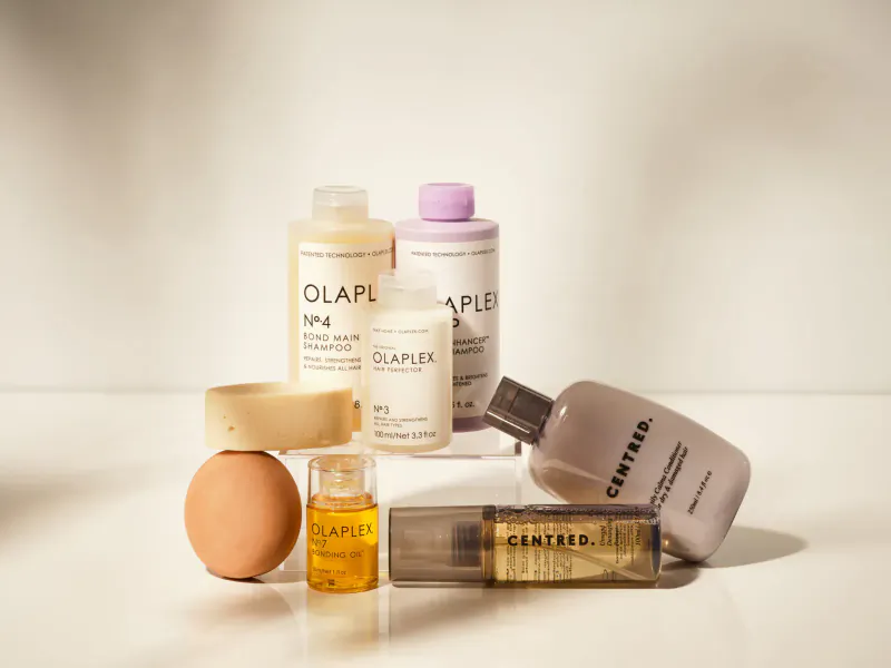 Olaplex No.4 shampoo, conditioner, No.9 oil, Centred conditioner, serum, and egg on white surface