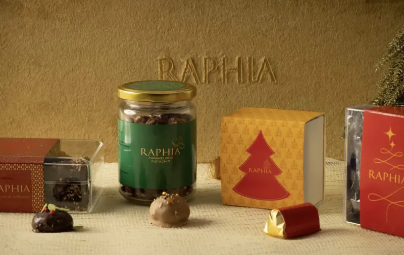 Raphia Christmas chocolates: jar of beans, truffles, gold candy, festive red and gold boxes with trees and stars.