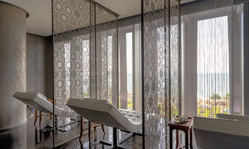 Elegant spa lounge at Naturelife Spa with reclining chairs, latticed screens, and sea view through large windows.