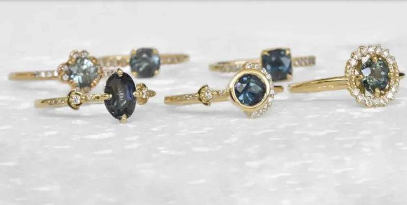Assortment of gold rings with grayish-blue gemstones on white surface