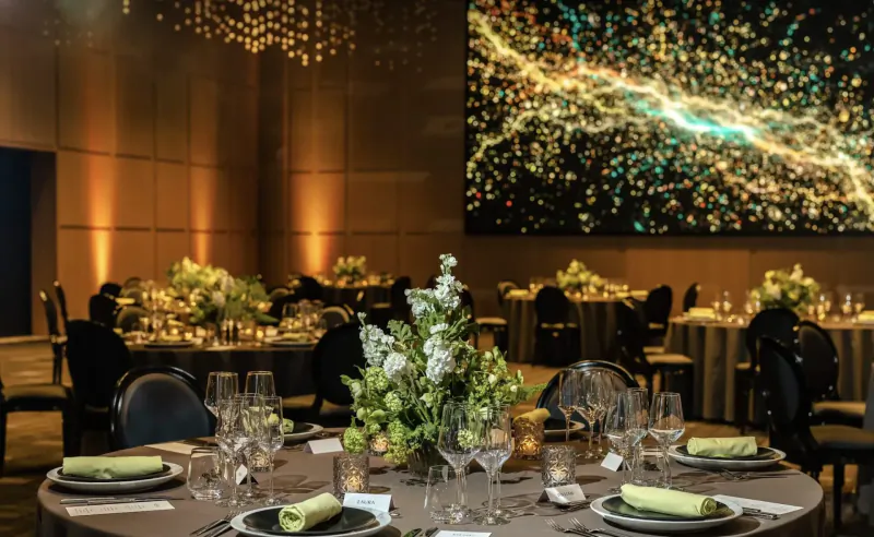 Elegant banquet hall at Pan Pacific London with cosmic video wall, candlelit tables, white flowers, and luxury seating.