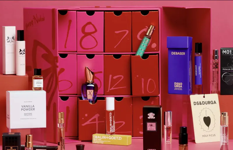 Open Byredo advent calendar with numbered pink doors revealing luxury perfumes, skincare, and powders.