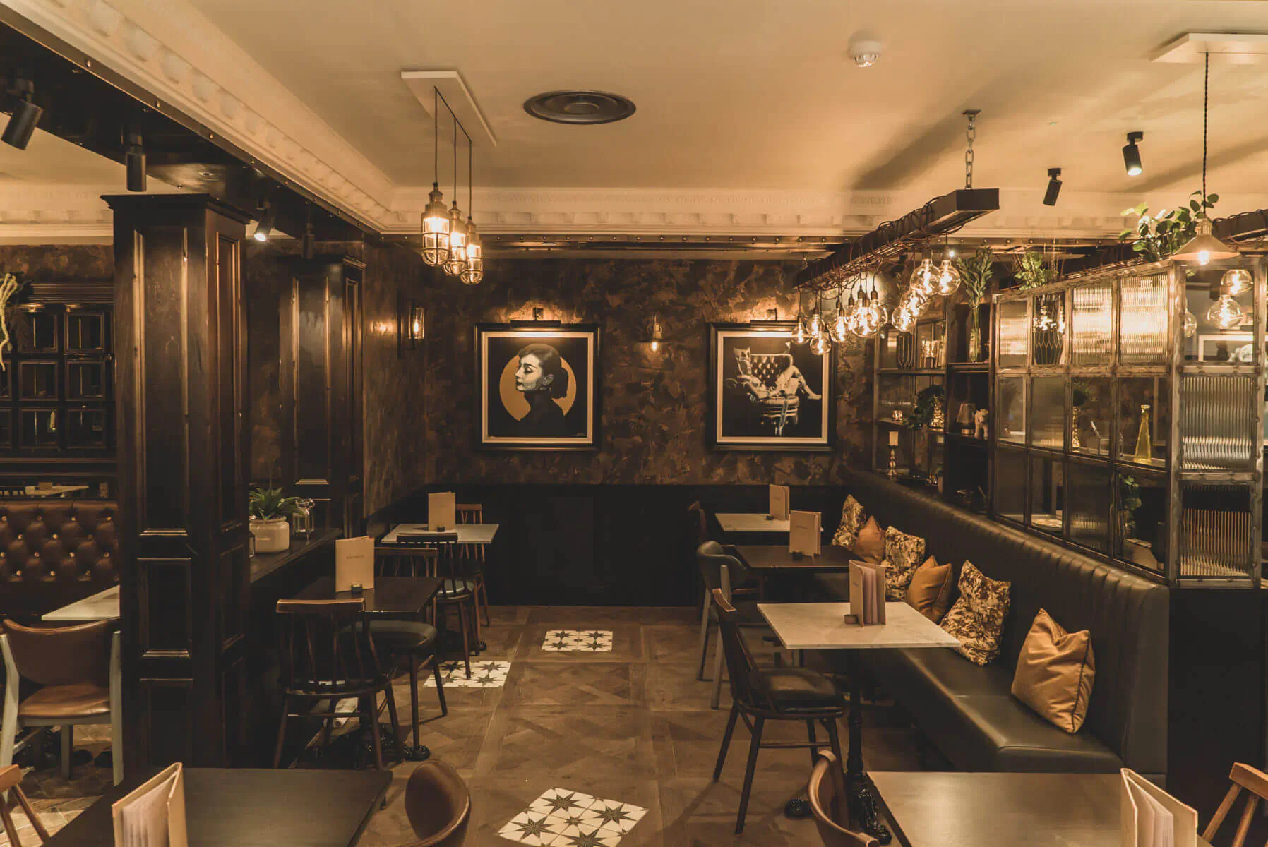 Cozy Six by Nico restaurant interior with wooden walls, pendant lights, black sofas, tables, and skull art.