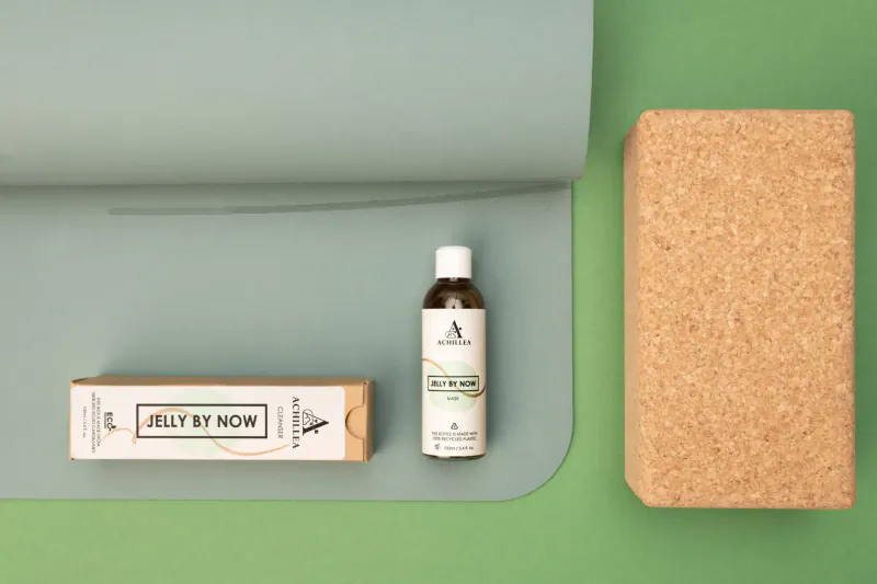 Jelly Now skincare bottle and box beside cork yoga block on green yoga mat
