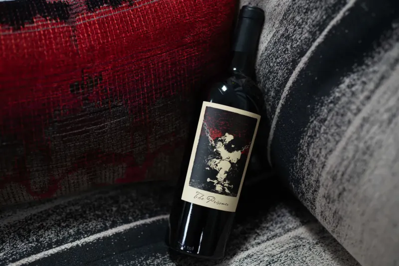La Branche red wine bottle with angel label on red patterned pillow and gray striped cushion
