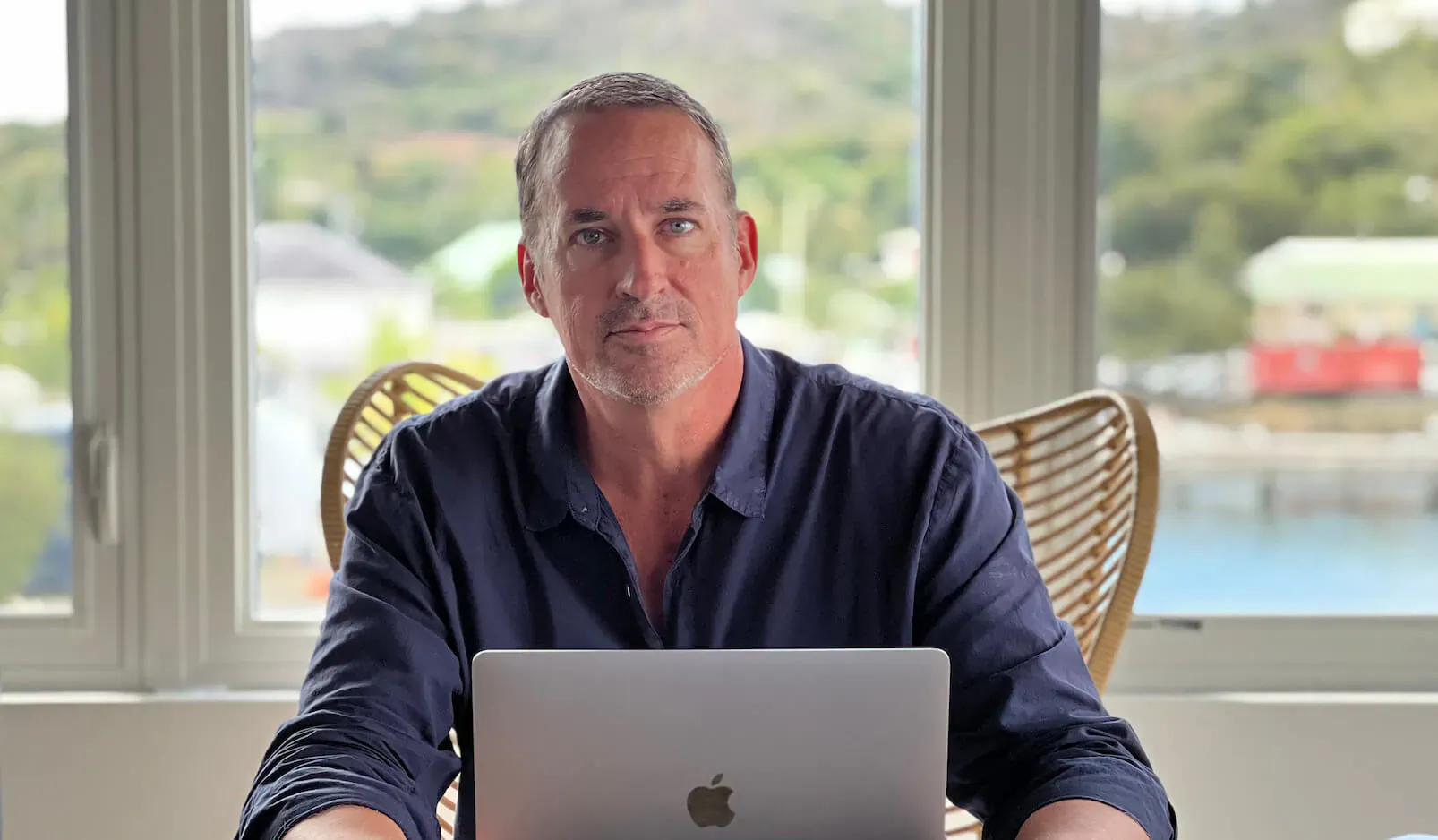 Brian Dobbin, Founder of Citizens International, seated at a laptop with ocean view in interview