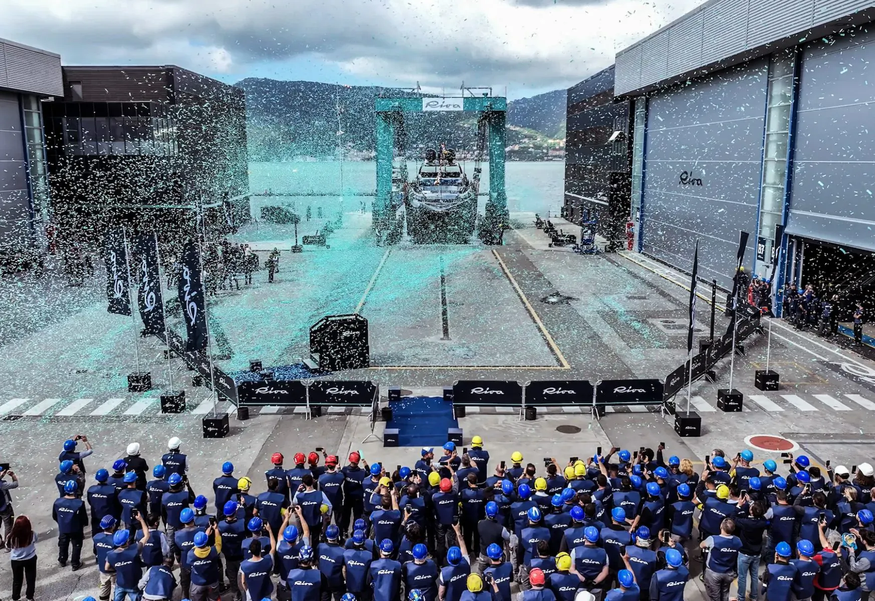 Ferretti Group opens refurbished La Spezia Shipyard: crowd in blue helmets cheers yacht launch amid confetti and gantries