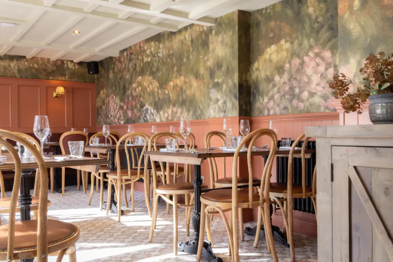 Elegant dining room at The George & Dragon Marlow with wooden tables, chairs, wine glasses, and floral wallpaper.