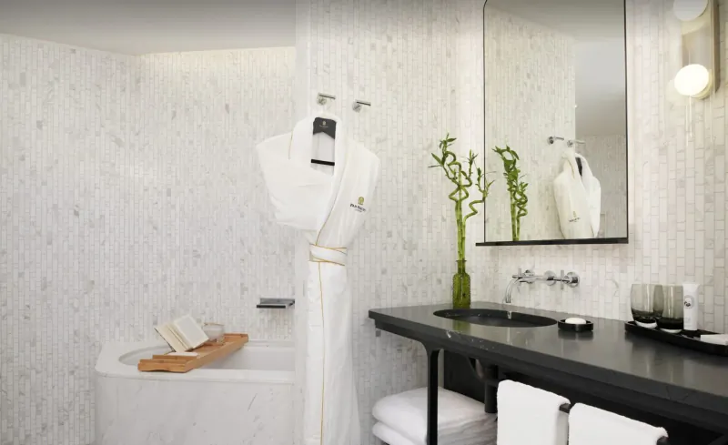 Luxurious Pan Pacific London bathroom with white tub, bathrobe, black vanity, bamboo, and towels.