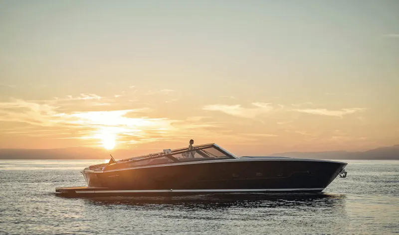 Sleek black Ferretti Yachts 720 on calm water at sunset, with figure on deck