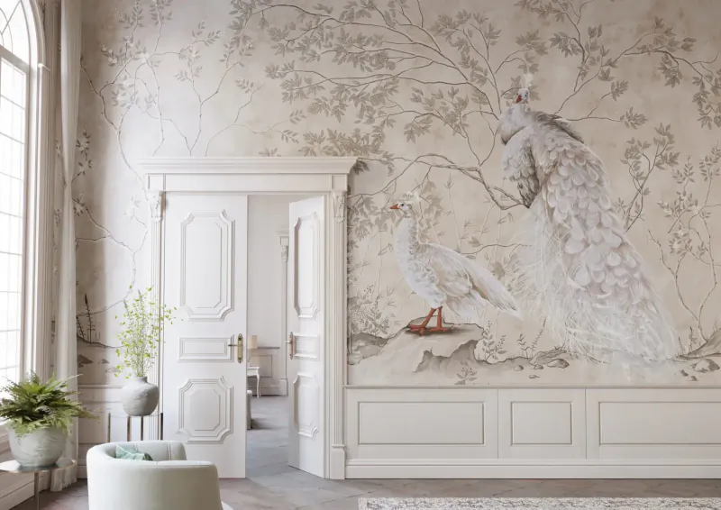 Elegant room with open white door, luxury beige wallpaper mural of peacocks, egrets, and trees, plants and pouf nearby.