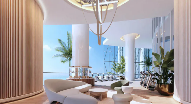 Modern Bentley Residences gym lounge with curved wood walls, white sofas, plants, gym equipment, and ocean views.